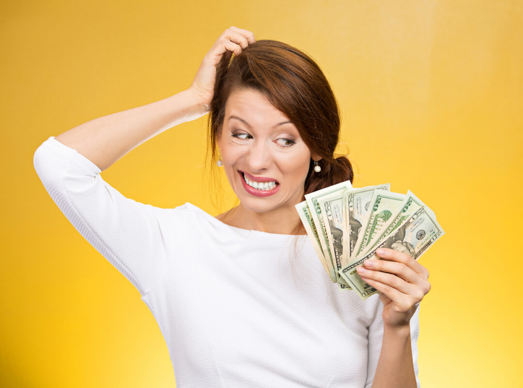 Closeup,portrait,,confused,pretty,woman,holding,cash,dollars,in,hand,