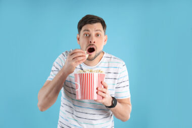 Emotional,man,with,tasty,popcorn,on,color,background