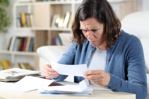 Confused,adult,woman,looking,at,receipts,sitting,in,the,livingroom