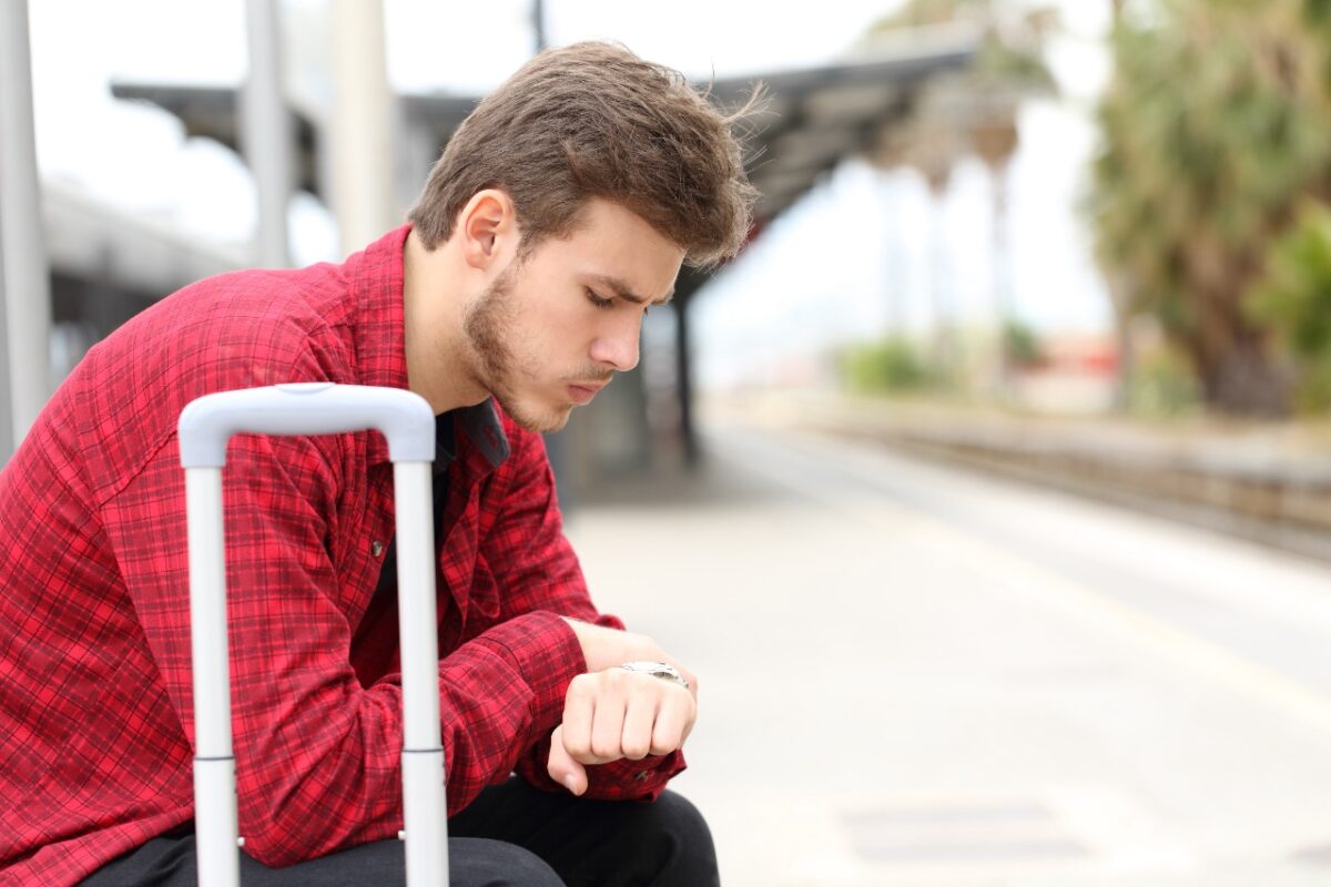 Worried,traveler,looking,at,his,watch,waiting,for,delayed,train