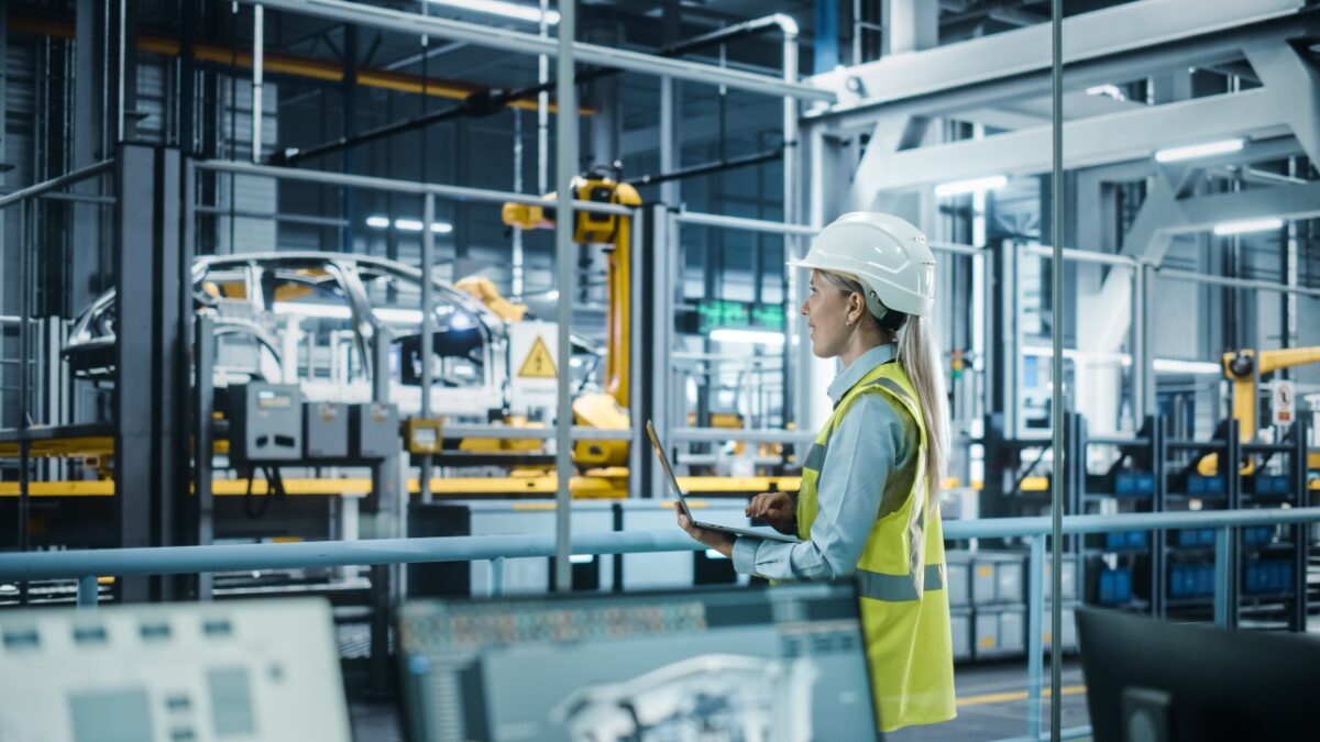 Car,factory:,female,automotive,engineer,wearing,hard,hat,,standing,,using