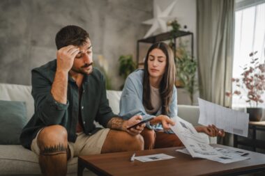 Adult,angry,and,serious,couple,sit,and,calculate,their,monthly