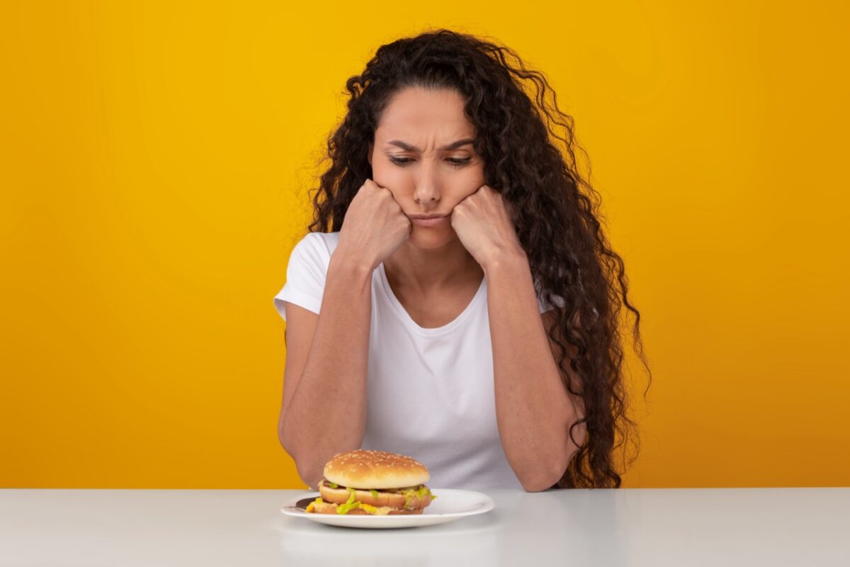 Diet,concept.,unsure,pensive,woman,looking,at,big,burger,on