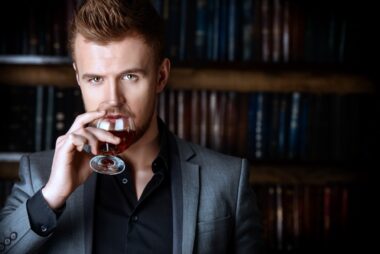 Elegant,man,in,a,suit,with,glass,of,beverage,stands