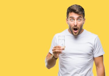 Young,handsome,man,drinking,glass,of,water,over,isolated,background