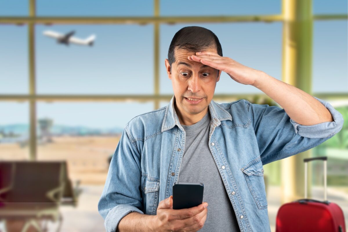 Man,texting,using,smartphone,at,airport,stressed,with,hand,on