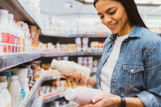 Happy,young,woman,shopping,for,yogurt,in,supermarket