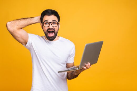 Shocked,astonished,amazed,bearded,man,in,eyeglasses,looking,at,laptop