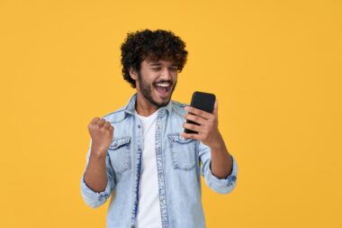 Excited,happy,young,indian,man,winner,feeling,joy,using,smartphone